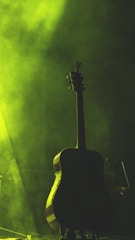 A moody, ethereal guitar silhouette bathed in violet and deep blue light.