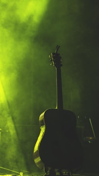 A moody, ethereal guitar silhouette bathed in violet and deep blue light.