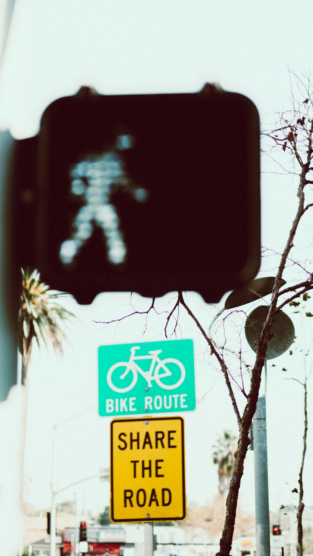 road signage with walk sign on near bike route road signage during daytime