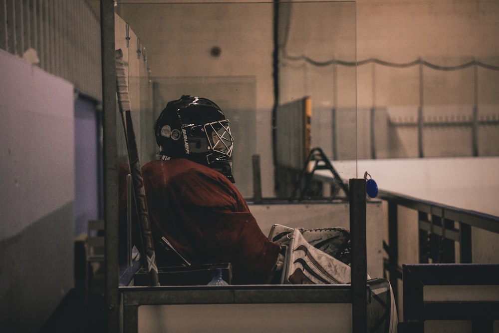 person sitting on bench wearing ice hockey jersey