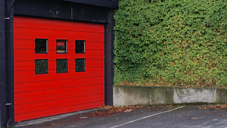 red and black wooden shed beside grass