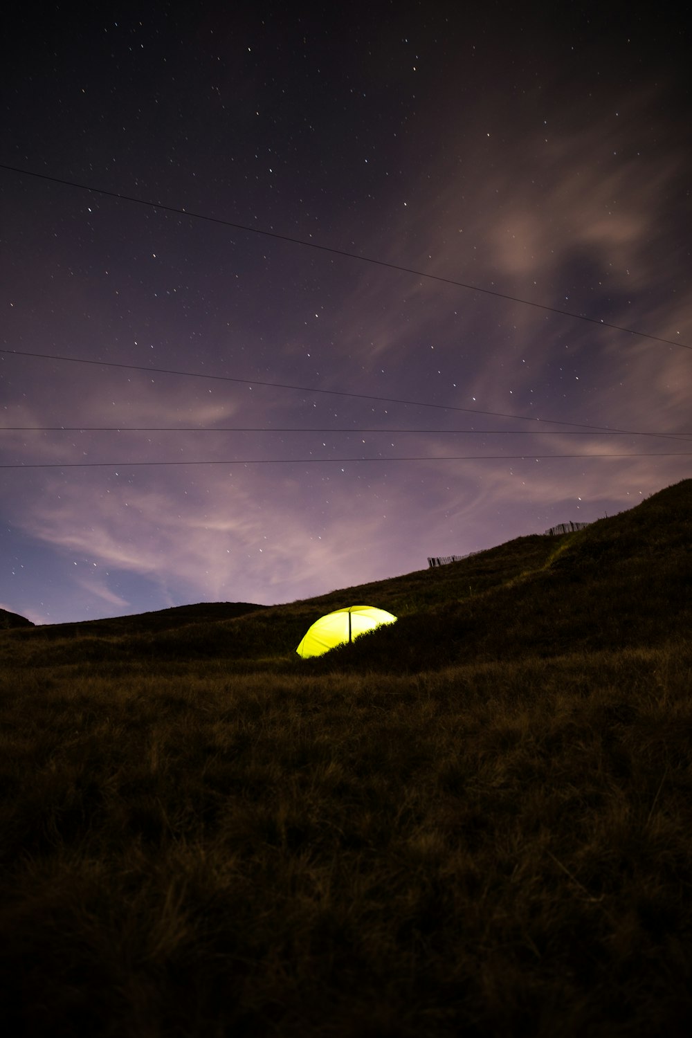 夜空の下でキャンプする黄色いドームテントの写真