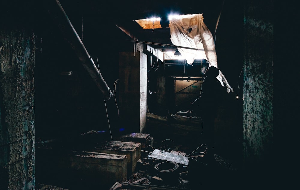 Photographie en basse lumière d’une personne à l’intérieur d’une pièce en désordre