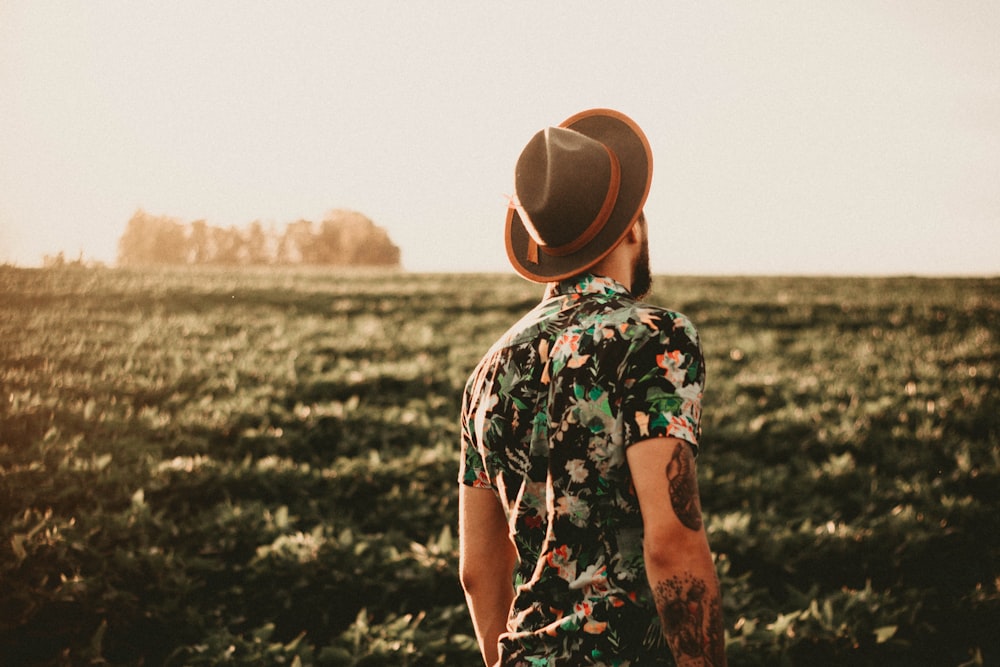 man wearing brown fedora hat standing near trees