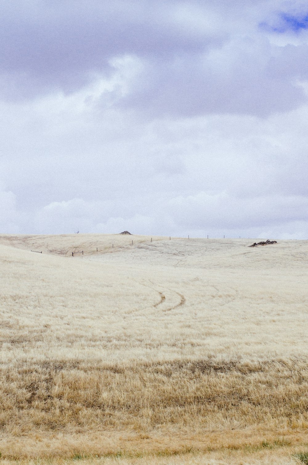 colina de grama marrom sob nuvens brancas durante o dia