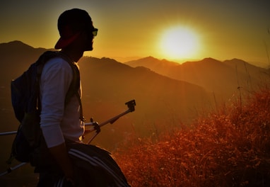 Hiker adjusting sunglasses while overlooking a mountain vista at sunset