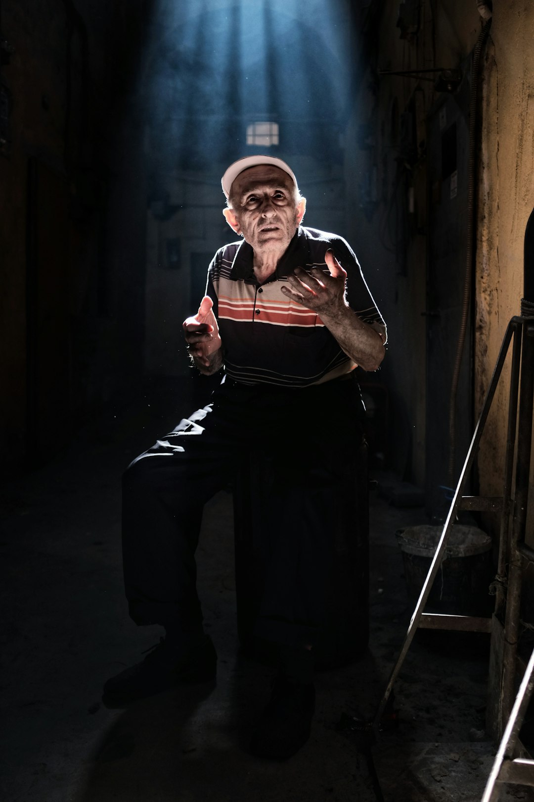 man wearing black and beige striped polo shirt and black pants sitting on stool with lights