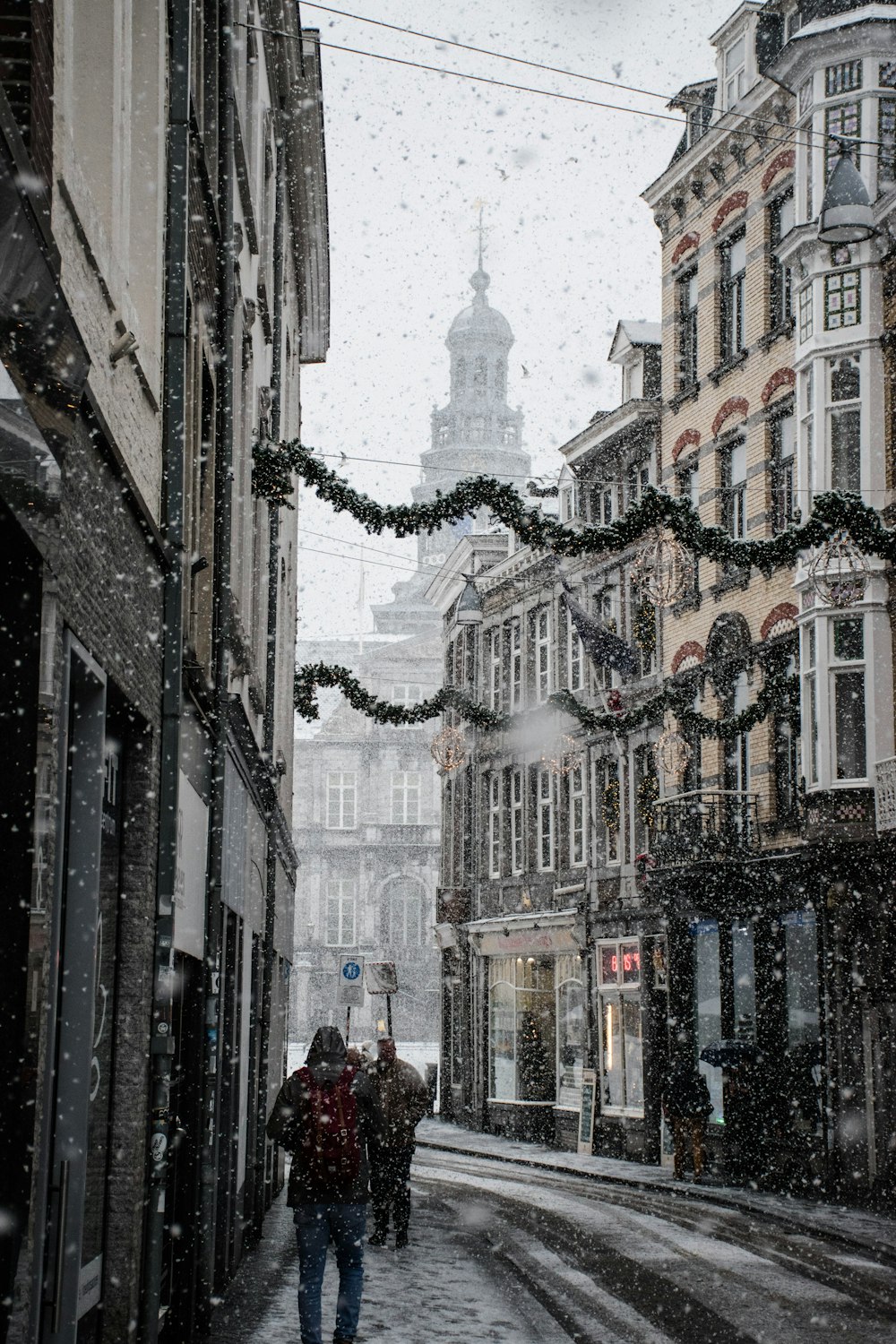 雪の季節に茶色の建物の間の通りの近くを歩く人々