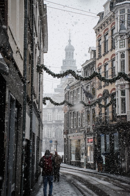 people walking near street between brown building during snow season in Maastricht Netherlands