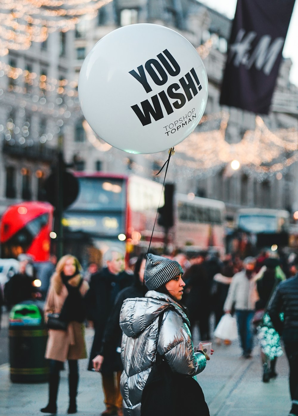 woman walking on street with people holding balloon at daytime