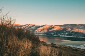 A serene lake reflecting snow-capped mountains during golden hour