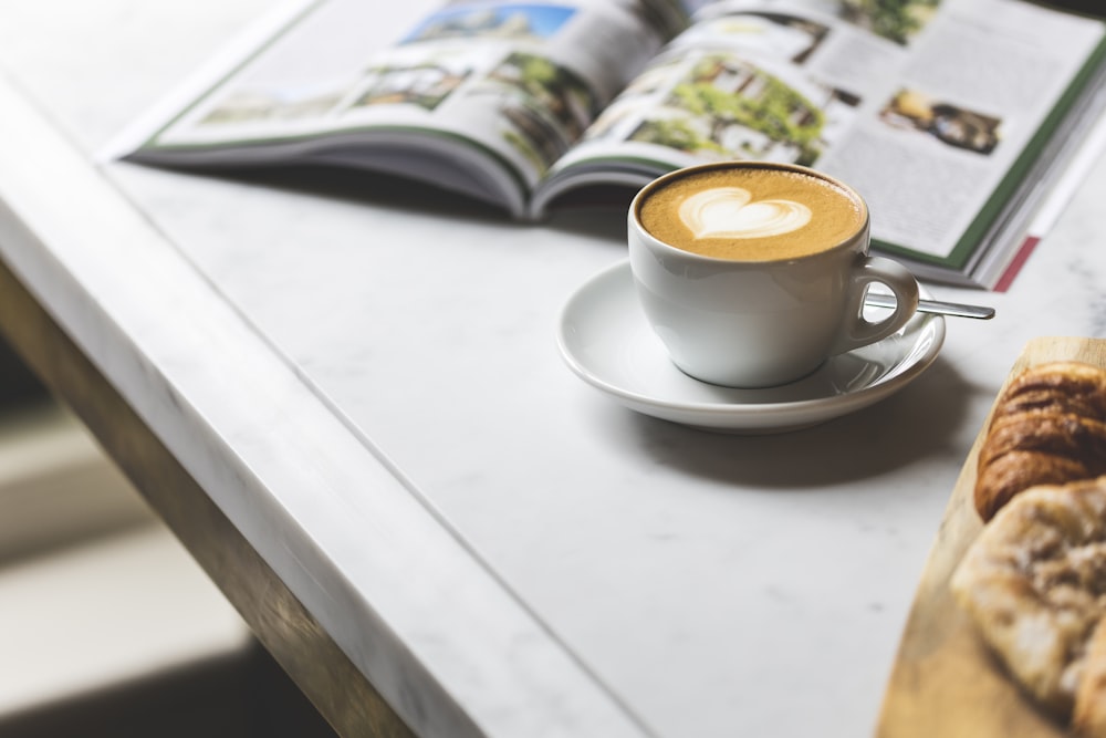 xícara de café de cerâmica branca com pires sobre mesa branca