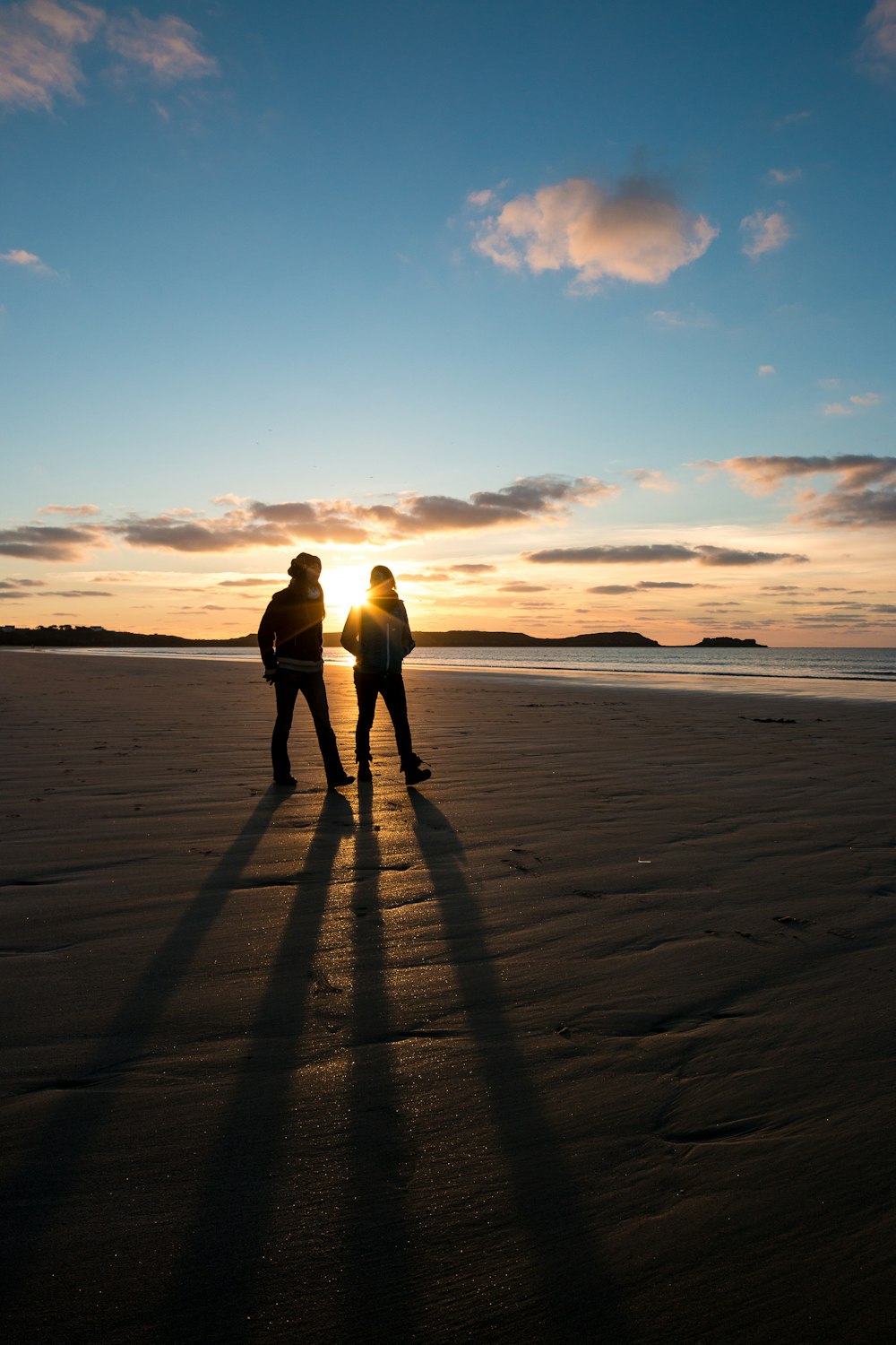 silhouette photo of two persons walking along seashore
