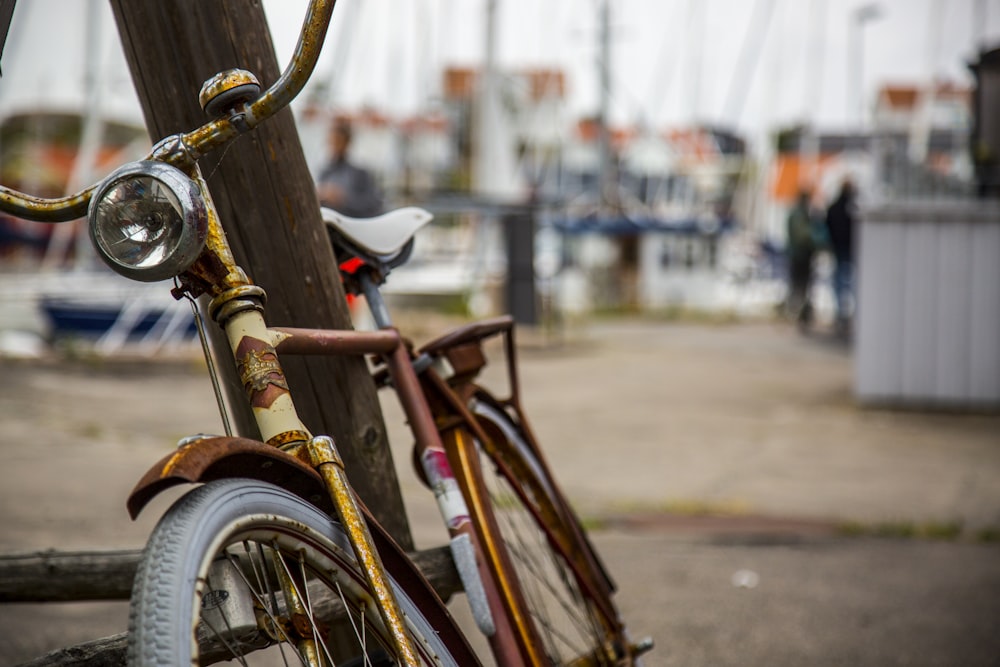 Photographie à mise au point peu profonde d’un vélo de ville s’appuyant sur un poteau en bois brun