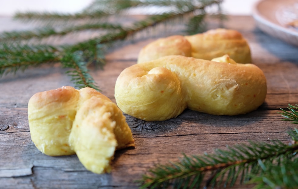 Close-up of freshly baked ka'ak and ma'amoul arranged on a rustic wooden tray with soft, warm lighting highlighting their golden textures