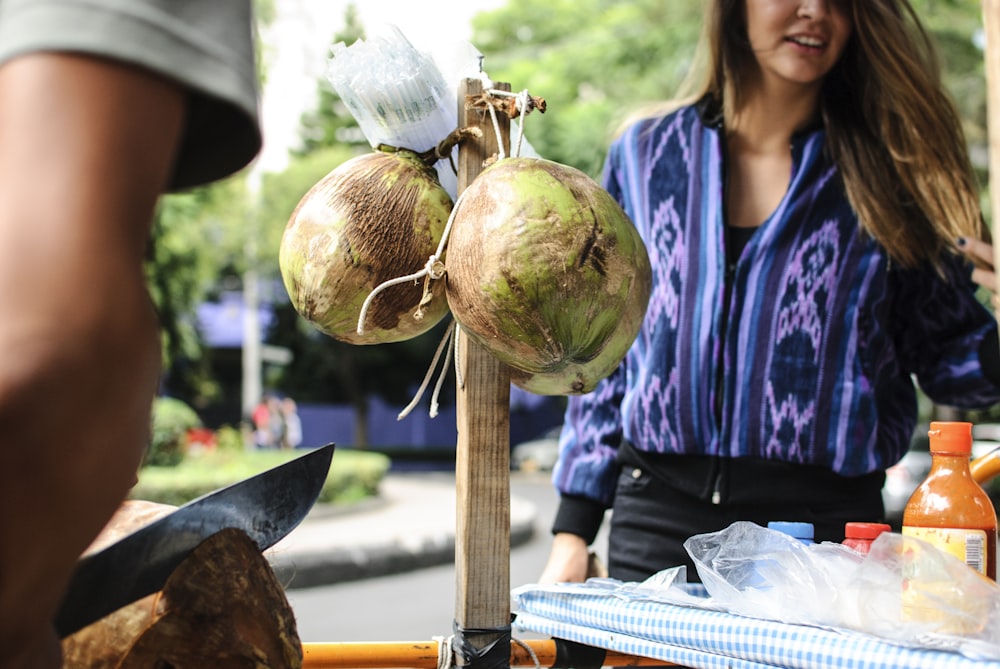 two green coconuts hanging on brown wooden bar