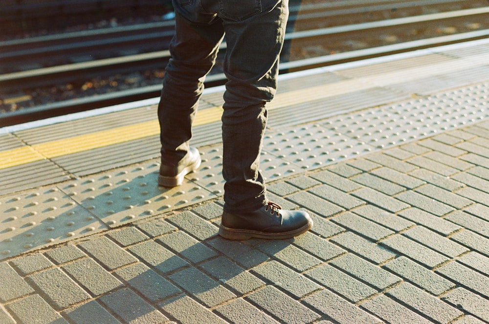 person wearing pair of black work boots standing on concrete blocks