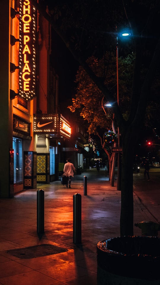photo of person walking beside a storefront during night time in Santa Monica United States