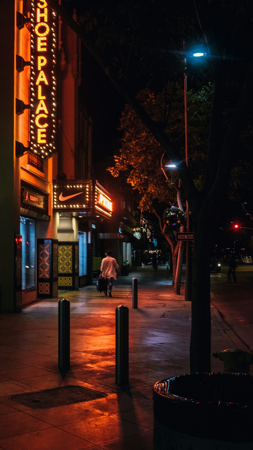 photo of person walking beside a storefront during night time