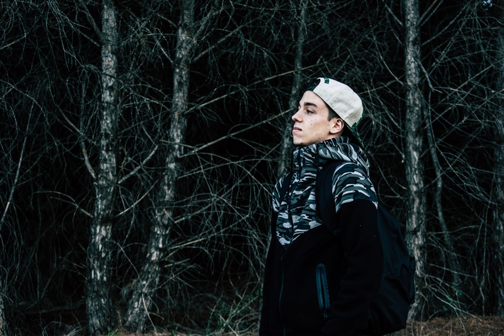 man in black and gray jacket standing near gray tree