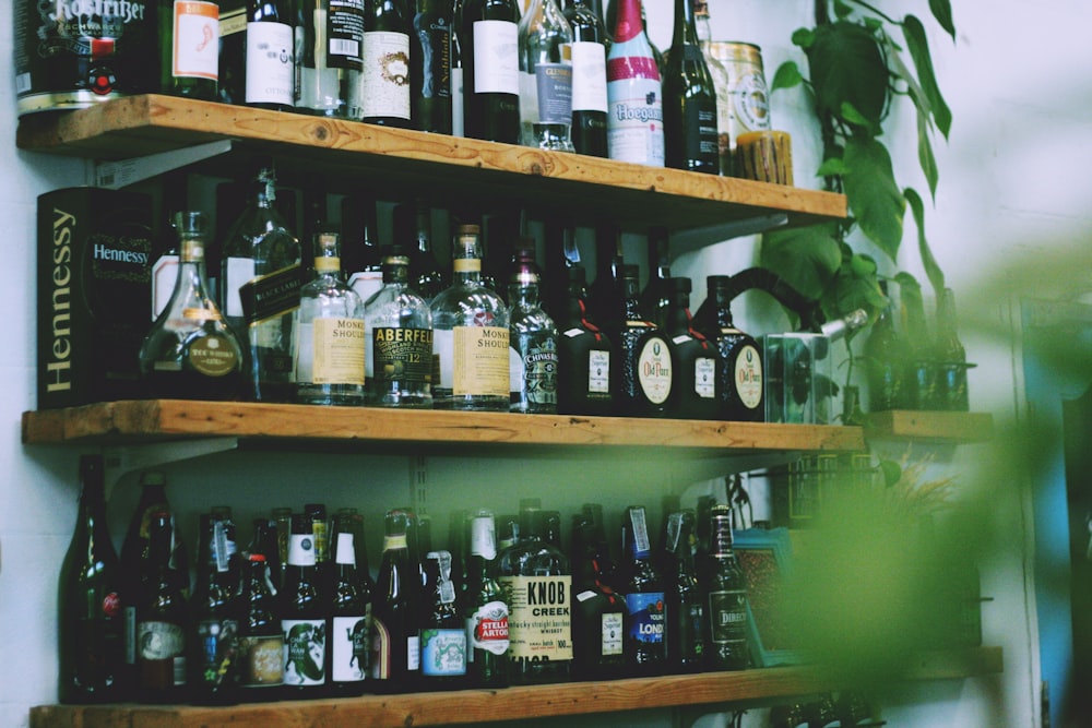 liquor bottles on brown wooden shelves closeup photography
