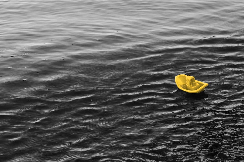 gelbes Plastikschiffsspielzeug, das auf dem Wasser schwimmt