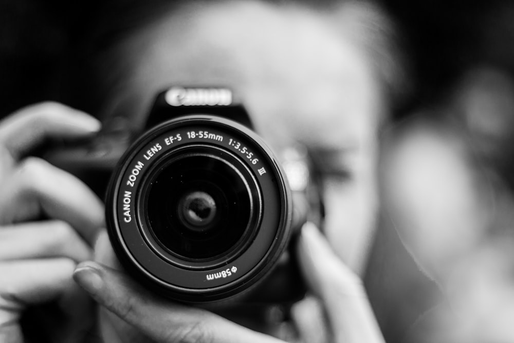 얕은 초점 렌즈에서 Canon 카메라를 사용하여 사진을 찍는 사람