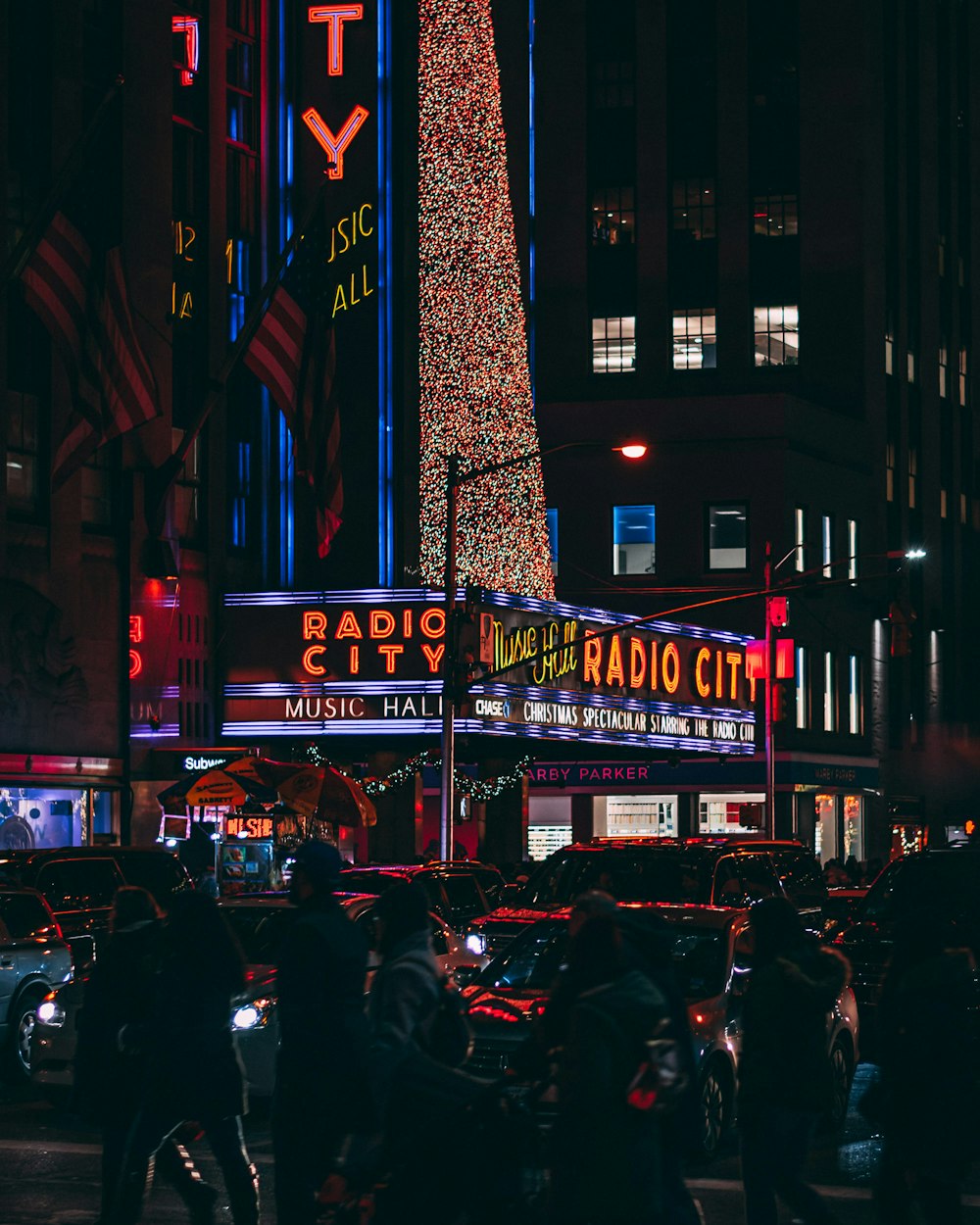 Personas y vehículos cerca de edificios con luces de neón