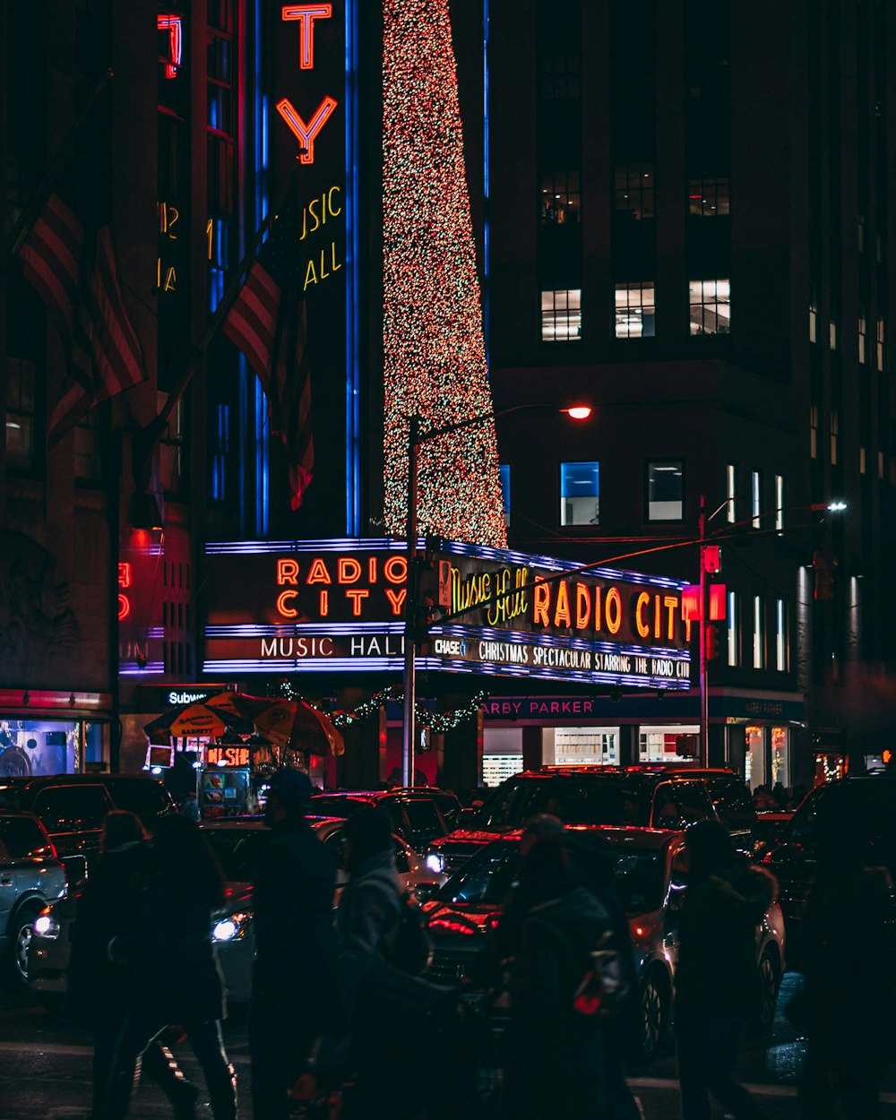 persone e veicoli vicino a un edificio con luci al neon