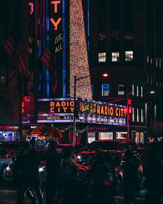people and vehicles near building with neon lights in Radio City Music Hall United States