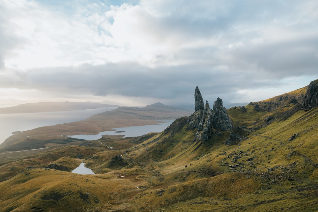 rock formation on hill near body of water under cloudy skies