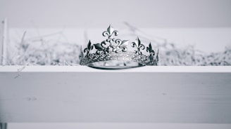 silver-colored crown on top of white wood