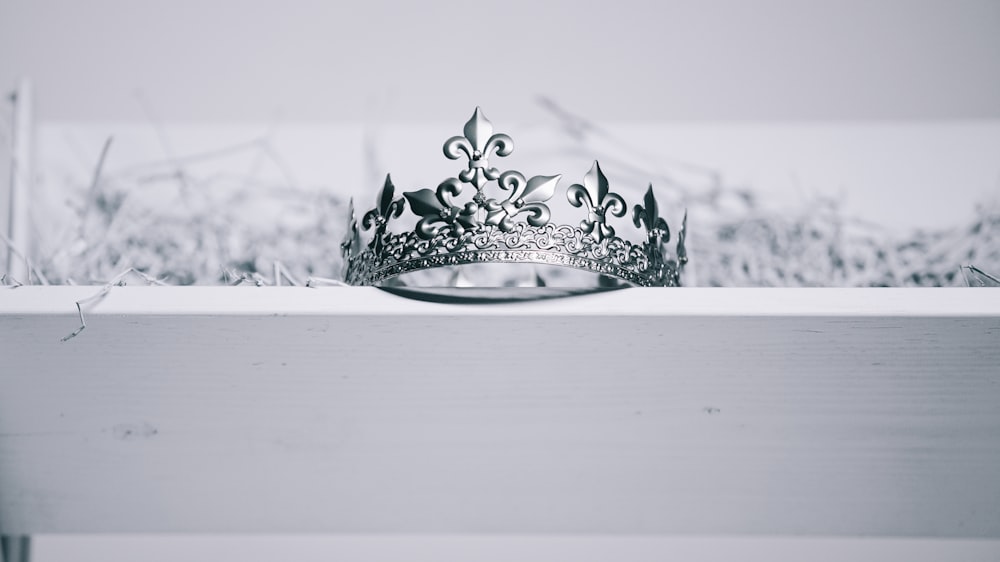 silver-colored crown on top of white wood