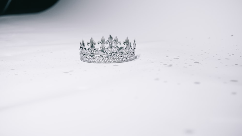 silver-colored crown ring on white surface