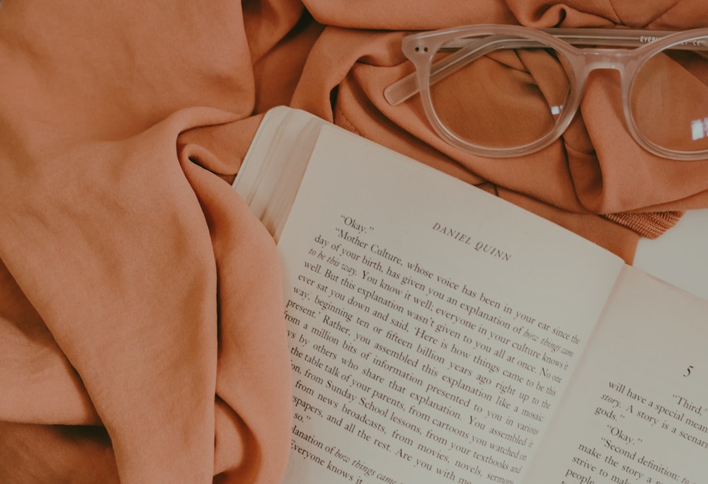 opened book page on top of pink mat near eyeglasses