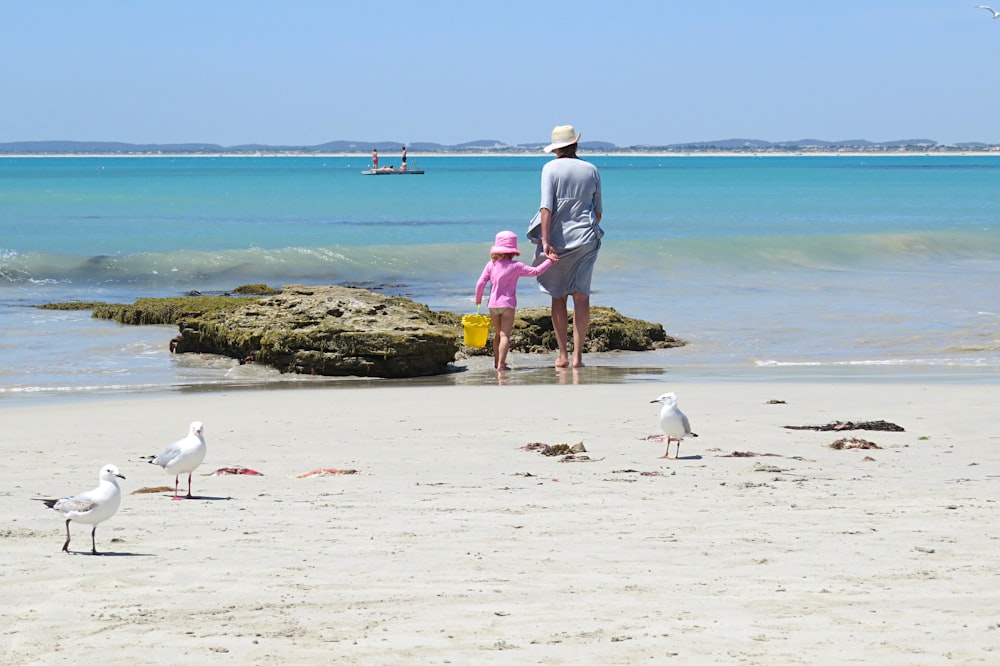 woman holding girl near beach during daytime