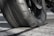 A close-up view of a worn motorcycle tire on a textured asphalt surface. The rubber appears smooth and the tread is nearly flattened, indicating significant use.
