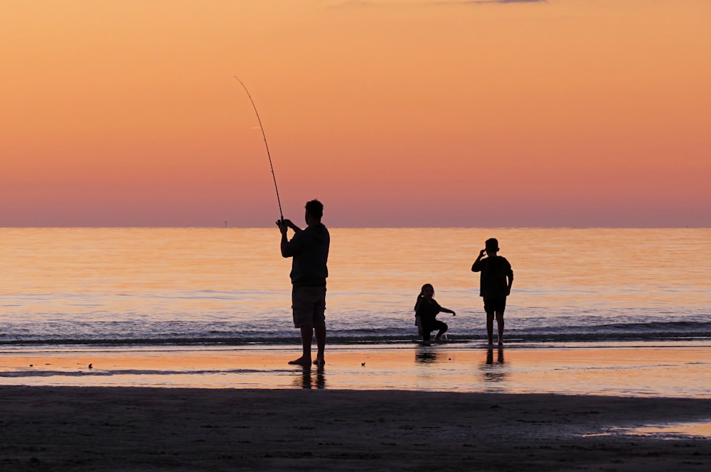 silhouette photo of a man fishing near shore during golden time