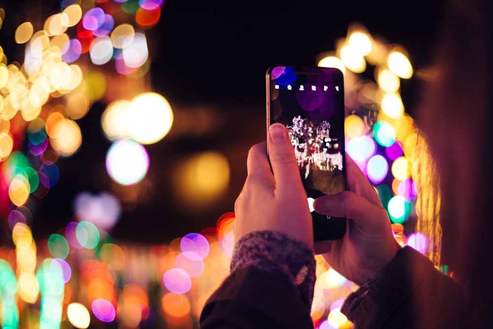 person taking photo of lights during nightime