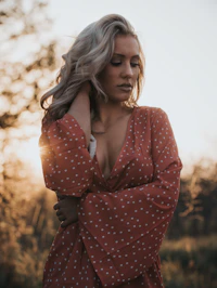 woman in white and red V-neck top holding her hair
