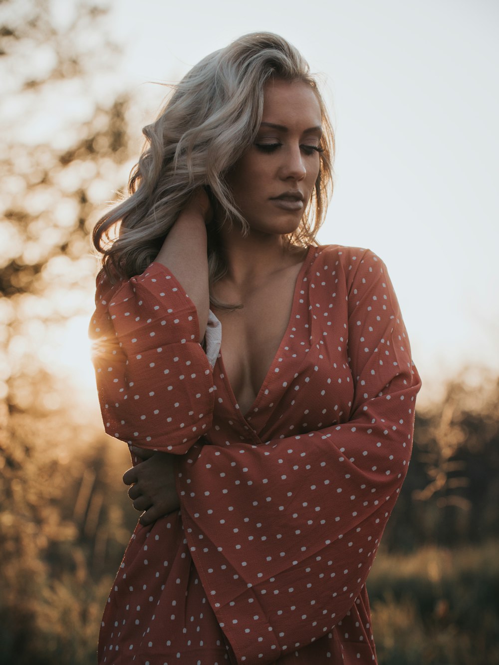 woman in white and red V-neck top holding her hair