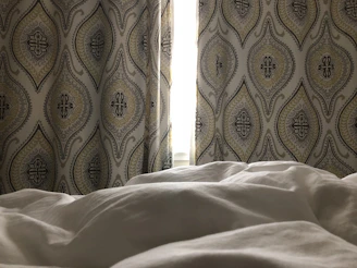 Elegant bedroom featuring muted tones, linen curtains, and soft lighting.