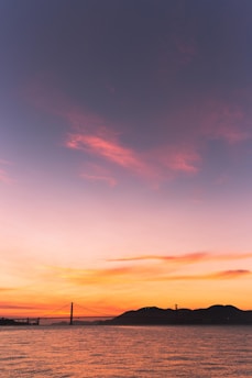 silhouette photography of mountain beside suspension bridge during golden hour
