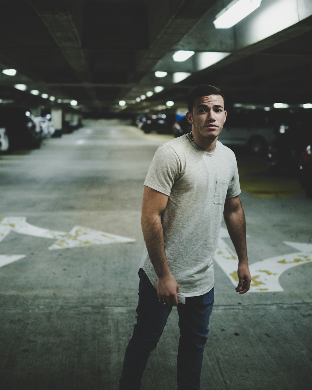 man standing inside parking lot surrounded by vehicles