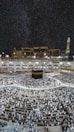 A large crowd of people gathered around the Kaaba, a cuboidal structure located at the center of the Grand Mosque in Mecca, Saudi Arabia. The image captures the scene at night, under a clear, starry sky. The mosque is surrounded by illuminated structures and features a prominent minaret on the right.