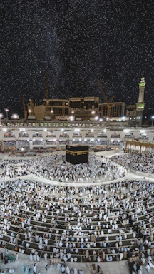 A serene evening view of Masjid al-Haram with pilgrims gathered around the Kaaba under soft golden lighting.