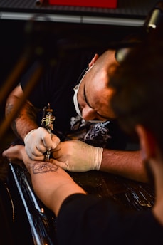 man doing tattoo on human arm