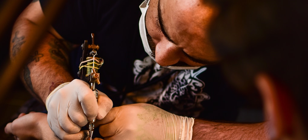 man doing tattoo on human arm