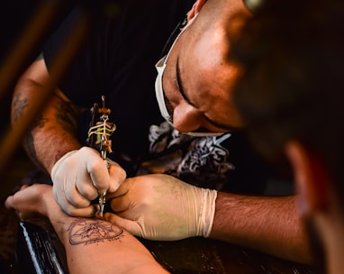 man doing tattoo on human arm
