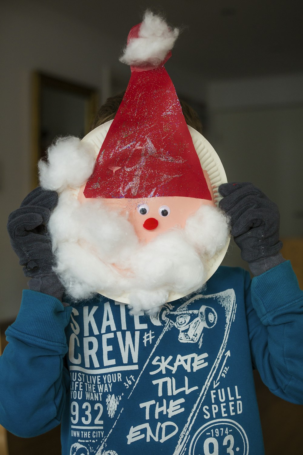 persona che tiene un piatto di carta bianco con la testa di Babbo Natale all'interno della stanza